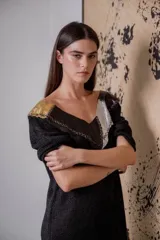 Vestido corto negro de tejido de punto con cuello en V, mangas 3/4, flecos en el ruedo y apliques de cuero en escote y hombros.