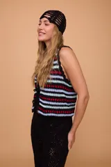Chaleco tejido a crochet con rayas horizontales en negro, celeste y rojo. Tiene escote en V y se ata en el frente con lazos.