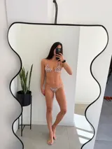 Conjunto de bikini con estampado de cebra en tonos marrones y blancos. El corpiño es triangular con tirantes finos y la bombacha es tipo colaless con tiras finas.