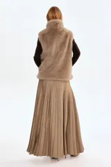 Chaleco de tejido suave con efecto de pelo sintético en color tostado. Presenta cuello elevado, cierre frontal de cremallera, sisas amplias y bolsillos laterales discretos. Posee un elástico oculto en el bajo para una silueta abullonada y está completamente forrado.