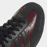 Championes Adidas Samba OG color borgoña con detalles en negro, con las tres tiras características de la marca en los laterales.