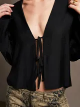 Blusa negra con estampado animal print en blanco y marrón, escote en V con lazo ajustable y mangas largas acampanadas.