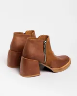 Botas cortas de cuero negro con textura de piel de serpiente, cierre lateral con cremallera, taco de madera forrado en cuero y punta fina.