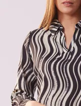 Blusa de gasa estampada en blanco y negro, marca Sioni. Tiene cuello con solapa y escote en V, mangas largas con puño fruncido.
