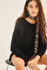 Sweater negro de moldería holgada, liviano y de caída relajada. Con aplicación de tachas termofijadas que expanden desde el hombro hacia el bajo ruedo de forma radial.