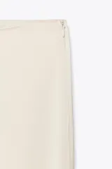 Pantalón de vestir color crema de tela satinada, corte palazzo y tiro alto.