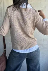 Sweater beige de hilo con cuello redondo y mangas largas.