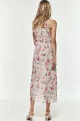 Vestido largo con estampado floral, cuello redondo y tirantes finos. Presenta elástico en la cintura con aberturas y lazadas laterales, volantes en el mismo tejido, forro interior a contraste y abertura frontal en el bajo. Cierre en la espalda con botón.