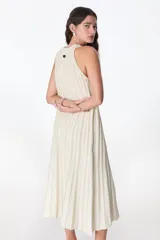 Vestido largo de tejido de punto, color celeste con rayas verticales en azul oscuro y brillo sutil por el lurex. Diseño sin mangas con cuello halter y silueta en A.