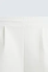 Bermuda color arena de tejido interlock de algodón con elasticidad, corte relaxed fit, cintura elástica ajustable con cordón interior, bolsillos laterales y bolsillo trasero de plastrón.