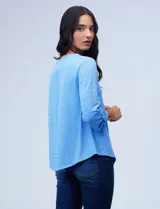 Blusa texturada de color celeste, con cuello a la base y escote en V, manga larga regulable.