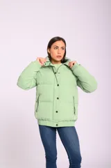 Campera puffer acolchada color verde claro, con cuello alto, cierre con botones a presión y bolsillos laterales con cierre.