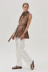 Chaleco largo marrón de algodón con cuello camisero, cierre frontal con botones, bolsillos laterales y lazo ajustable en la cintura.