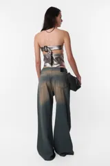 Corset strapless plateado de cuerina PU con cinto en la espalda con hebilla y ojalillos metálicos para ajuste y cierre metálico para acceso a la prenda. Detalle de recortes en delantero y espalda que simulan ballenas.