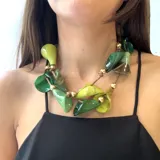 Collar de resina con diseño de calas en tonos verdes y amarillos, con cuentas de resina dorada y cierre de botón.