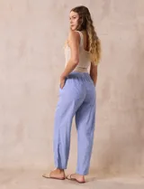 Pantalón largo de lino y rayón a rayas verticales grises y blancas. Tiene pretina elastizada con lazo de ajuste, bolsillos delanteros y traseros.