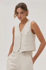 Chaleco sastrero color beige de lino y viscosa metalizado, con cuello en V y cierre con botones.