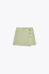 Minifalda pantalón color verde claro, de tiro alto, con frente cruzado y cierre lateral con botones.