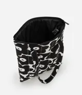 Funda para notebook con diseño tipo cartera, confeccionada en algodón con estampado floral bicolor en blanco y negro. Tiene cierre de cremallera y asa mediana.
