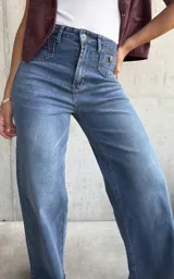 Jean de mujer color azul claro, de corte recto y tiro alto, con bolsillos delanteros decorativos con solapa y botón.