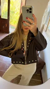 Campera marrón de ecocuero con cuello clásico, corte holgado y cierre frontal con botones a presión.