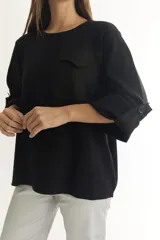 Sweater color beige de tejido de punto suave y liviano, con cuello redondo, manga larga con botón decorativo y bolsillo de parche en el pecho.