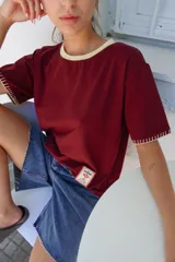 Remera de algodón color azul marino, corte relajado con hombro caído. Presenta cuello redondo blanco y bordado a mano en contraste en los puños de las mangas. Tiene un parche bordado en la parte inferior del frente.