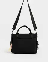 Cartera tipo tote de tela deportiva color negro, con correa regulable desmontable, manijas superiores, charm lateral con la palabra "Vibes", cierre superior, bolsillo frontal y bolsillos laterales de red.