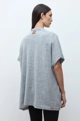 Ruana de tejido de punto color rosa melange, sin mangas y con cuello redondo.