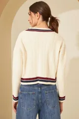 Cardigan celeste de punto trenzado, con escote en V y botones metálicos. Presenta ribetes a contraste en cuello, puños y bajo.