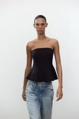 Top negro palabra de honor con peplum, confeccionado en tejido elástico con forro interior y cierre de cremallera oculta en la costura.