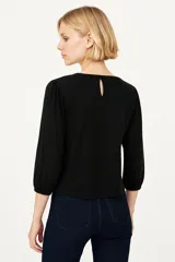 Remera color marfil con cuello redondo y mangas 3/4 abullonadas.