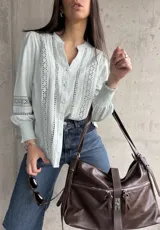 Camisa celeste con bordado inglés, cuello mao y mangas largas abullonadas con puños elásticos.