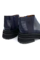 Bota de cuero azul con diseño de textura de cocodrilo, con cierre lateral y suela gruesa.