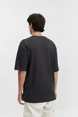 Remera negra de manga corta con corte oversize y estampado gráfico blanco en el frente que incluye un mapa del mundo y figuras geométricas.