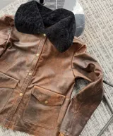Chaqueta de cuero vacuno color óxido con efecto gastado y cuello de cordero azul marino intenso.