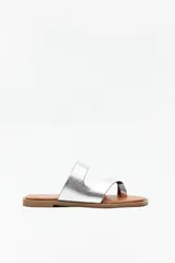 Sandalias bajas plateadas con tiras de cuero sintético y agarre en el dedo gordo.