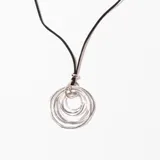 Collar con colgante de múltiples aros plateados de diferentes tamaños, unidos entre sí y suspendidos de un cordón negro.