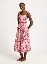 Falda midi con estampado floral en tonos fucsia y beige, con cintura alta y corte acampanado. Presenta una faja a rayas horizontales en la cintura y en el ruedo.