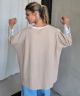 Remerón beige de corte amplio, con escote redondo y mangas largas.