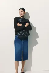 Pollera midi de jean azul, de cinco bolsillos, con tajo frontal y cierre con botón.