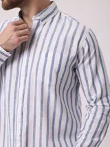 Camisa de manga larga a rayas verticales azules y blancas, con cuello abotonado y bolsillo en el pecho. Confeccionada en lino y algodón.