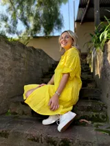 Vestido camisero corto de lino color amarillo, con cuello camisero, mangas cortas con botón, cierre frontal con botones y corte holgado.
