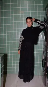 Buzo de punto negro con cuello alto y bordado blanco en las mangas.
