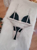 Conjunto de lencería de algodón color verde inglés con detalles de encaje nude, compuesto por un bralette de corte triangular con breteles regulables y una tanga con laterales ajustables.