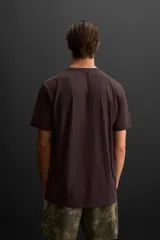 Camiseta deportiva marrón de tejido técnico ligero y elástico con estructura. Cuello redondo, manga corta, costuras planas y logo estampado.