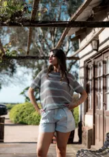 Remera de hilo tejido a rayas horizontales grises y celestes, de corte suelto y mangas cortas.