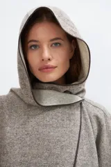 Ruana color crudo de lana fina sin teñir, con capucha, bolsillos y terminaciones envivadas. Tiene un broche para usar cerrada. Es una prenda oversize sin forro, cómoda, versátil y fácil de combinar.