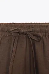 Shorts mini color marrón de tiro medio con cintura elástica ajustable con lazada y bolsillos laterales.
