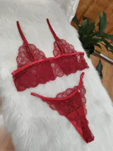 Conjunto de lencería de dos piezas color rojo, compuesto por un bralette de encaje floral con tirantes finos ajustables y una tanga a juego con bordes festoneados.